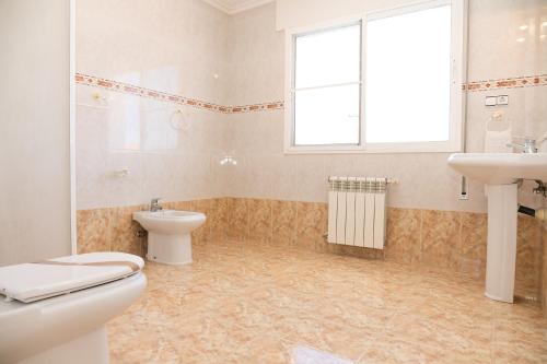 a bathroom with a toilet and a sink and a window at VILLA ADELAIDA in L'Eucaliptus