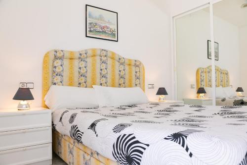 a bedroom with a bed with a black and white comforter at VILLA ADELAIDA in L'Eucaliptus