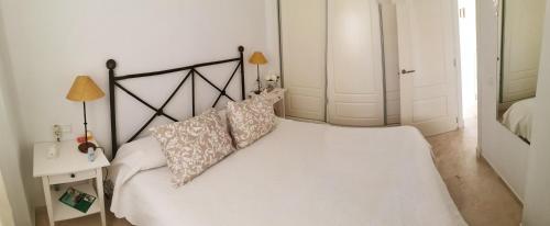 - un lit blanc avec des oreillers dans la chambre dans l'établissement APARTAMENTO CASARES PLAYA, à San Luis de Sabinillas