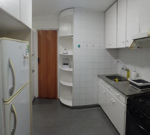 cocina con armarios blancos y nevera blanca en Departamento en el Centro Histórico de Rosario en Rosario