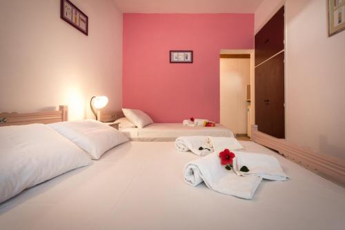 two beds in a room with pink walls at Pansion Limni in Keri