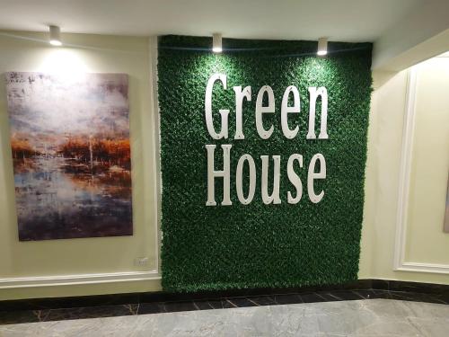 a green house sign on a wall in a room at Green House Hotel in As Suways