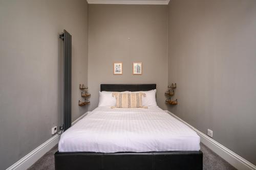a bedroom with a large bed with white sheets at Vibrant Leith Flat in Edinburgh