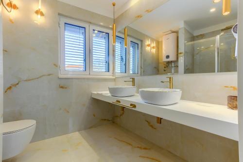 a bathroom with two sinks and a toilet and a mirror at Irini Luxury Rooms in Split