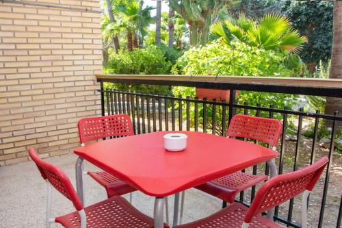 a red table with four chairs and a cup on it at APARTAMENTOS PALASIET in Benidorm