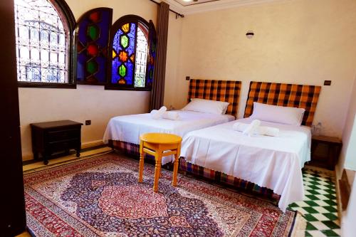 a bedroom with two beds and a table and a window at VILLA YOUSRA in Marrakech
