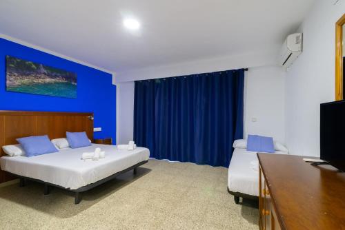 a bedroom with two beds and a blue wall at APARTAMENTOS PALASIET in Benidorm