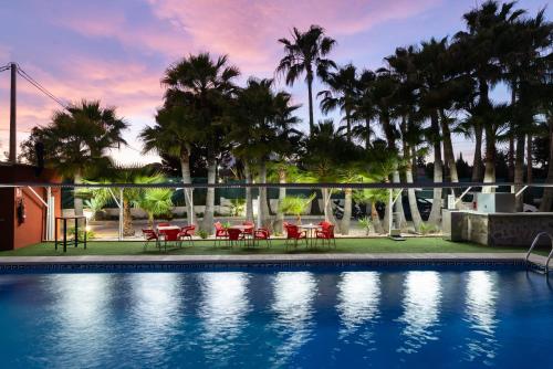 a swimming pool with tables and chairs and palm trees at APARTAMENTOS PALASIET in Benidorm