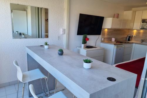 une cuisine avec un grand comptoir blanc avec des plantes dessus dans l'établissement Naturiste Cap d'Agde Port Vénus 104, au Cap d'Agde