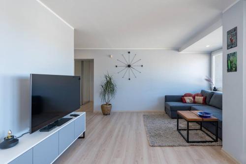 ein Wohnzimmer mit einem TV, einem Sofa und einer Uhr in der Unterkunft Central 2 BD Apartment by Hostlovers in Kaunas