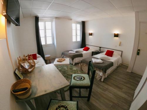 Habitación pequeña con 2 camas y mesa. en Le Petit Hôtel, en Biarritz