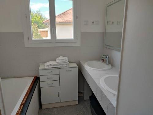 W białej łazience znajduje się umywalka i lustro. w obiekcie Petite maison de 70m2 très calme w mieście Bellerive-sur-Allier