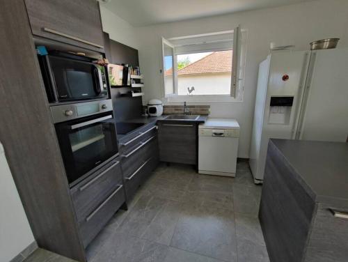 une cuisine avec un évier et un micro-ondes dans l'établissement Petite maison de 70m2 très calme, à Bellerive-sur-Allier