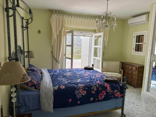 una camera da letto con un letto con un piumone blu e una finestra di Villa Los Faramondos Naturehouse a Turre