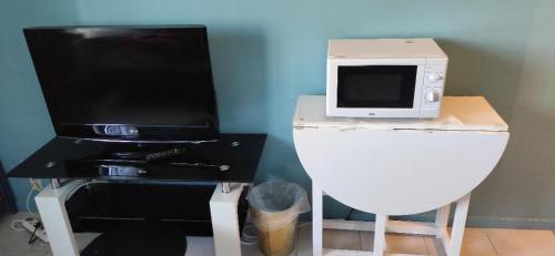 un microondas sentado en la parte superior de un mostrador junto a una mesa en Studio au calme en Péronnas