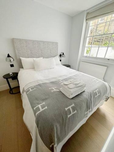 um quarto branco com uma cama grande e 2 toalhas em Londwell, Luxe and Leaves, Chelsea Flat with Private Garden em Londres