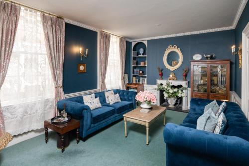 a blue living room with two blue couches and a table at Abbey Mews in the heart of Bath in Bath