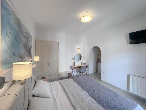 a white bedroom with a large bed and a desk at ATHANASIA APARTMENTS in Skiathos Town
