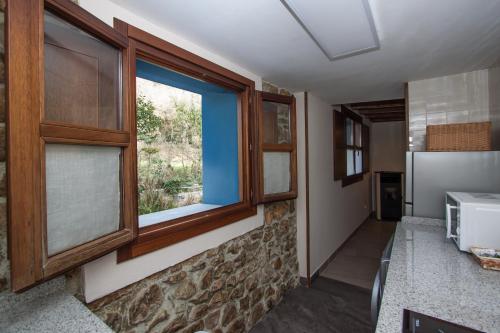 a kitchen with two windows and a refrigerator at Madre Rosa I, casa rural con la playa a 12 km in Llanes