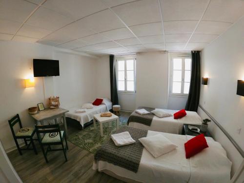 Ein Zimmer mit 2 Betten und einem Tisch und ein Zimmer mit in der Unterkunft Le Petit Hôtel in Biarritz