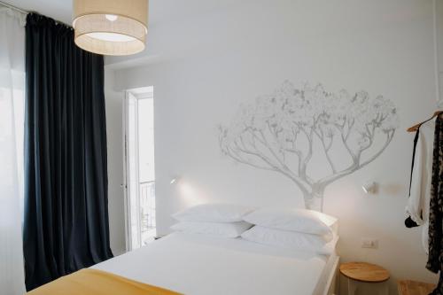 a bedroom with a white bed with a tree mural on the wall at PETRARCA17 Guest house a due passi dal mare in Terracina