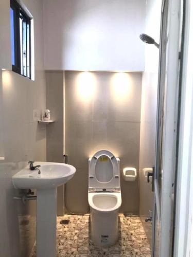 a bathroom with a white toilet and a sink at The VeeHive Guesthouse in Moalboal