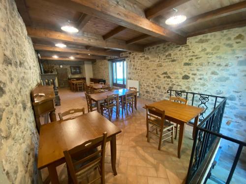 a restaurant with wooden tables and chairs and a stone wall at Agriturismo Prunara Farmstead F.lli Santoli in Monzuno