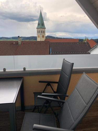 a table and two chairs on a balcony with a building at Alpenblick in Leutkirch im Allgäu