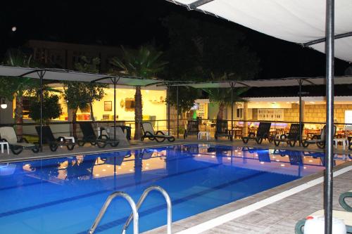 a pool at night with tables and chairs at Hotel Gold Stone in Beldibi