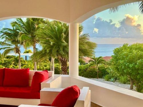 a living room with a red couch and a view of the ocean at VillaDelSol-Ocean Front Resort-Pool-up to 8 Guests-Walk to the Beach in Willibrordus