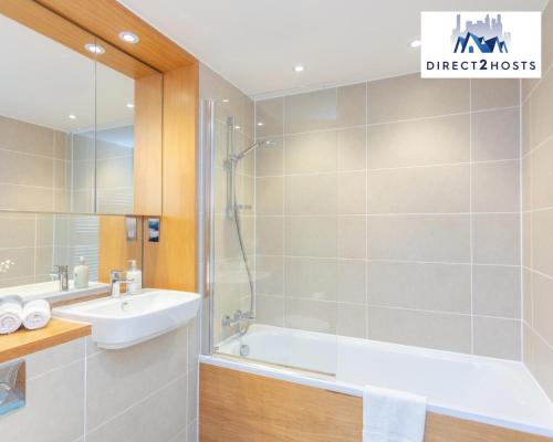 a bathroom with a shower and a sink and a bath tub at Stylish & Comfy One Bedroom Apartment By Direct2hosts in Great East London location! in London