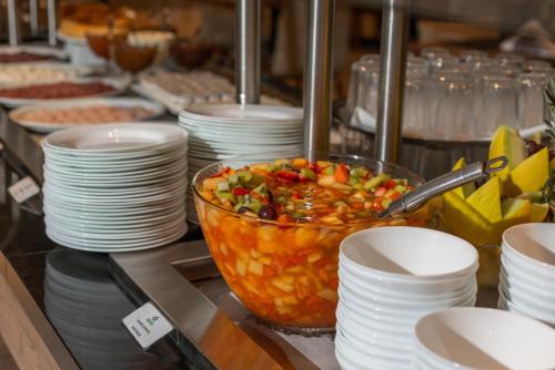 Hotel Laghetto Rio Grande في ريو غراندي: بوفيه بأطباق بيضاء ووعاء من الطعام