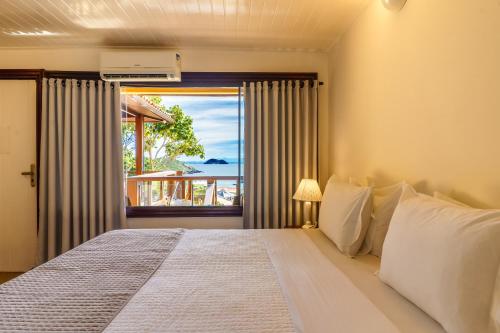a bedroom with a bed with a view of the ocean at Buzios Mar Hotel in Búzios