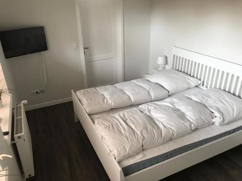 ein großes weißes Bett in einem Zimmer mit einem TV in der Unterkunft Ferienhaus Ankerplatz in Fehmarn