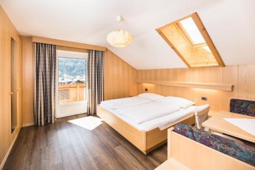 a bedroom with a bed and a desk and a window at Apartments Chalet Zirm in Santa Cristina in Val Gardena
