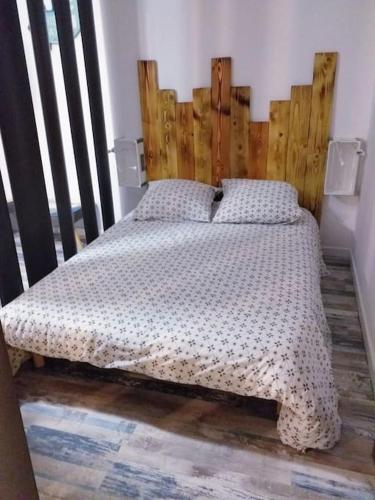 un lit avec une tête de lit en bois dans une chambre dans l'établissement Charmant studio climatisé proche de la mer, à Sanary-sur-Mer