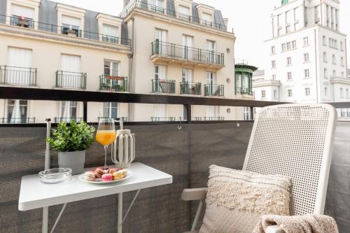 une table et une chaise sur un balcon avec un verre de jus d'orange dans l'établissement DisneyLand Paris Station 2min, à Chessy