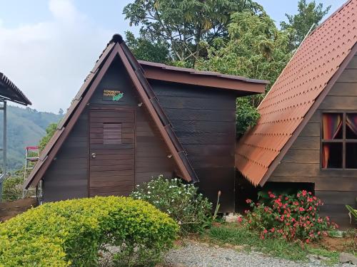 un petit bâtiment brun avec un toit rouge dans l'établissement Casa Tucan Glamping, à Turrialba