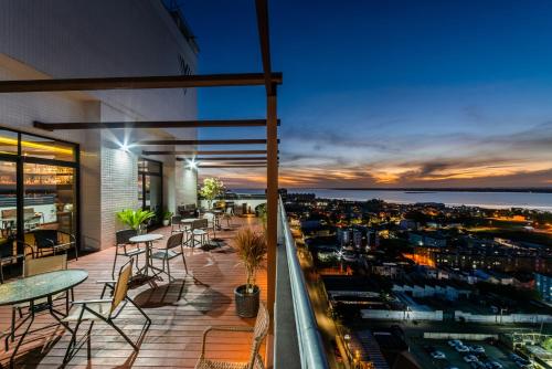 uma varanda com mesas e cadeiras e vista para a cidade em Hotel Laghetto Rio Grande em Rio Grande