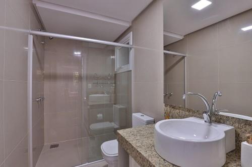 a bathroom with a shower and a sink and a toilet at Residencial London AP 104 in Gramado