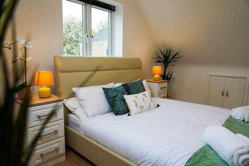 een slaapkamer met een bed met kussens en een raam bij Luxury 4-bed in Oxford with 2x parking & garden in Oxford