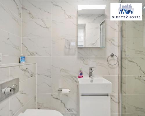 Baño blanco con lavabo y espejo en Bright and Stylish One Bedroom Flat by Direct2hosts Short Lets with great location! en Londres