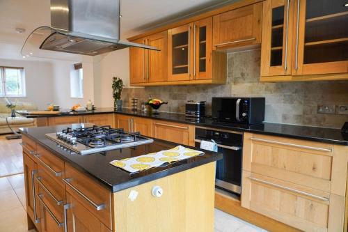 a kitchen with wooden cabinets and a stove top oven at Large 4-bed house for up to 7 guests w 2x parking in Oxford