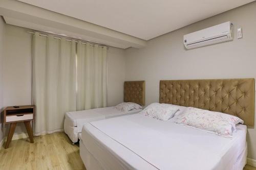 een slaapkamer met 2 bedden, een nachtkastje en een raam bij Residencial via Florida AP102 D in Gramado