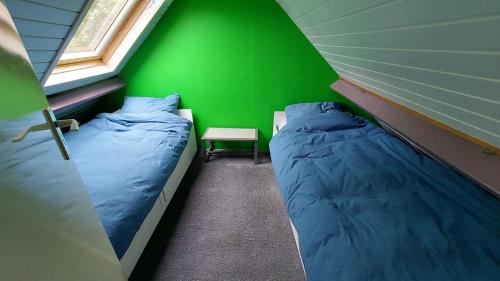 een kamer met 2 bedden en een groene muur bij Holiday Home Achterbos in Sint-Oedenrode