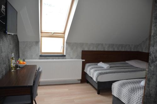 a bedroom with a bed and a table and a window at Willa Monte in Wisła