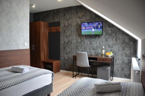 a bedroom with two beds and a desk with a television on the wall at Willa Monte in Wisła