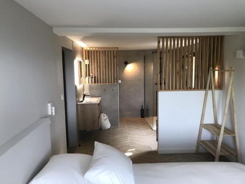 a bedroom with a white bed and a bathroom at Le Balcon in Castelvieilh