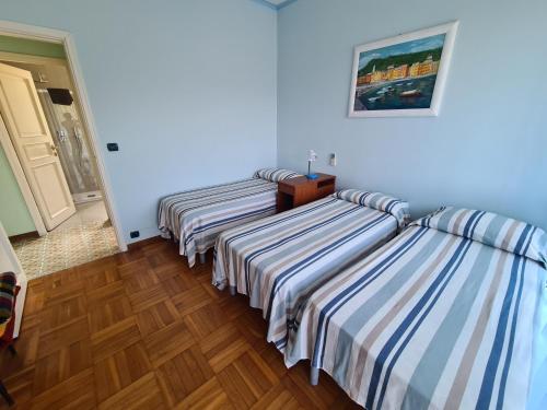 two beds in a room with blue walls and wooden floors at Grande Attico con Vista Vicino al Centro by PortofinoVacanze in Rapallo