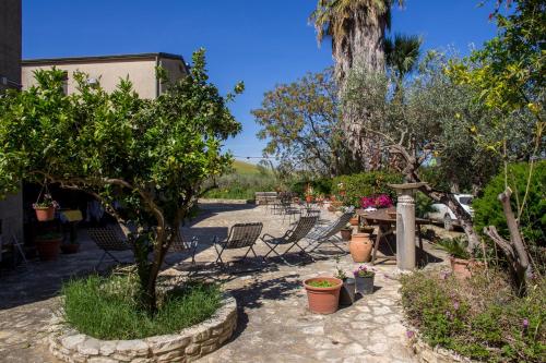 a patio with chairs and trees and plants at Agriturismo Tarantola in Alcamo